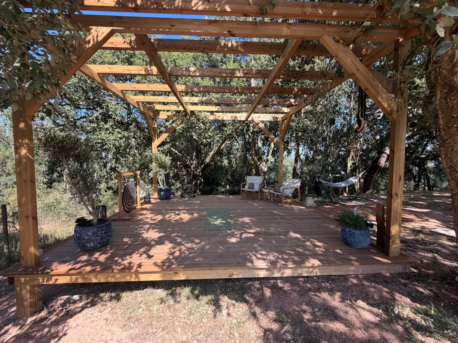 Open-air timber deck with seating beneath trees at Pathfinder Therapy’s Alcobaça nature-based practice